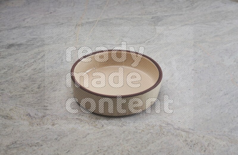 A beige pottery oven bowl on grey marble background