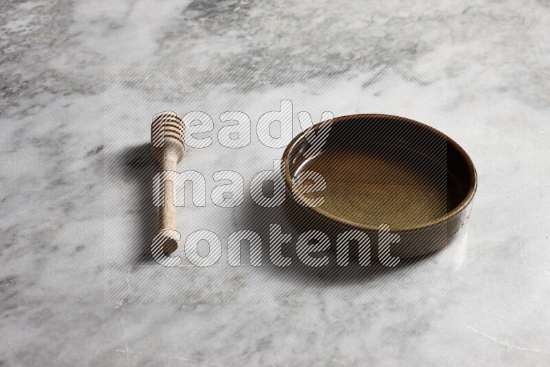 Multicolored pottery oven plate with wooden honey dipper on the side on grey marble background