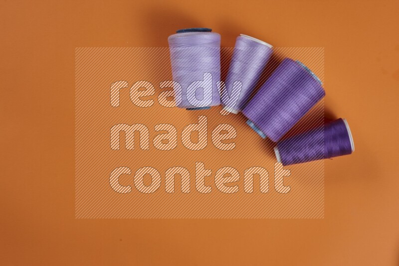 A purple collection of sewing and tailoring tools arranged on a orange background