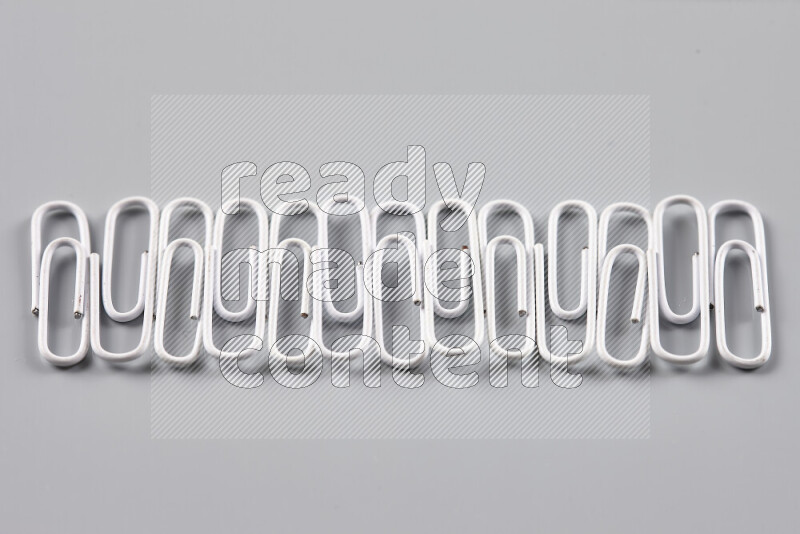 White paper clips isolated on a grey background