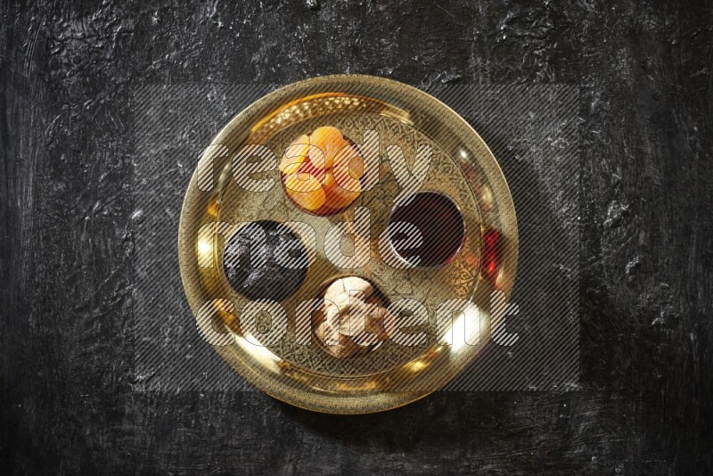 Dried fruits in metal bowls with Hibiscus on a tray in dark setup