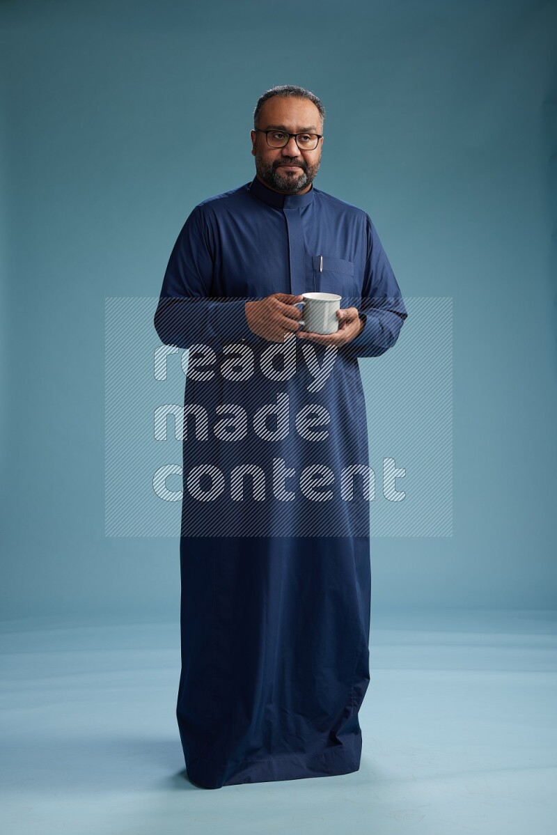 Saudi Man without shimag Standing drinking coffee on blue background