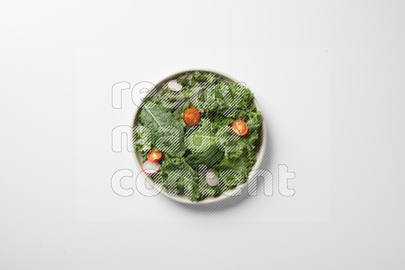 A bowl of fresh vegetables salad with kale leaves, cherry tomatoes, sliced radishes and sliced cucumber on a white background