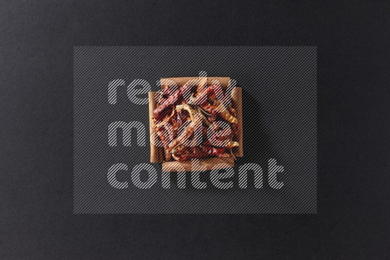 A single square of cinnamon sticks full of chilis on black flooring