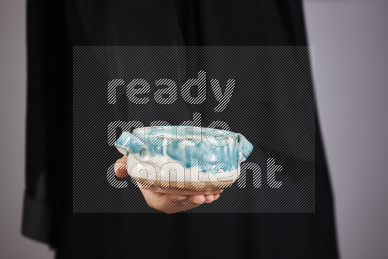 A woman in black abaya holding different pottery essentials in different positions