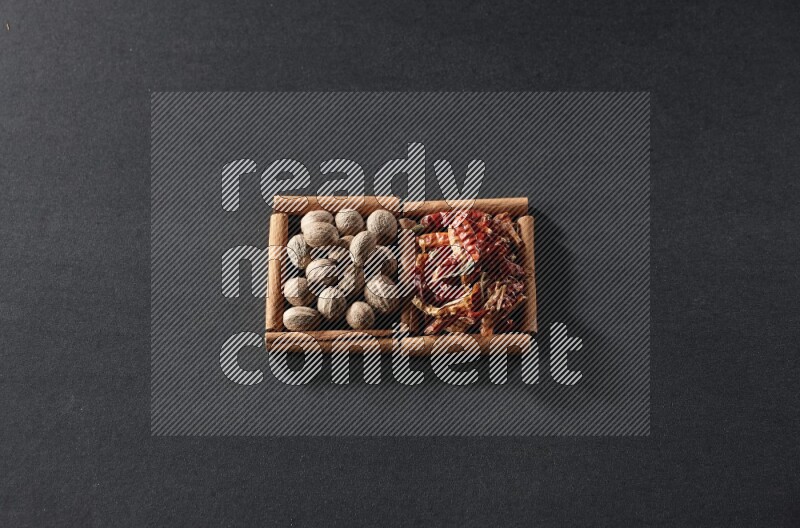 2 squares of cinnamon sticks full of nutmegs and dried red chilis on black flooring