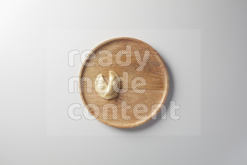 Two Sambosas on a wooden round plate on a white background