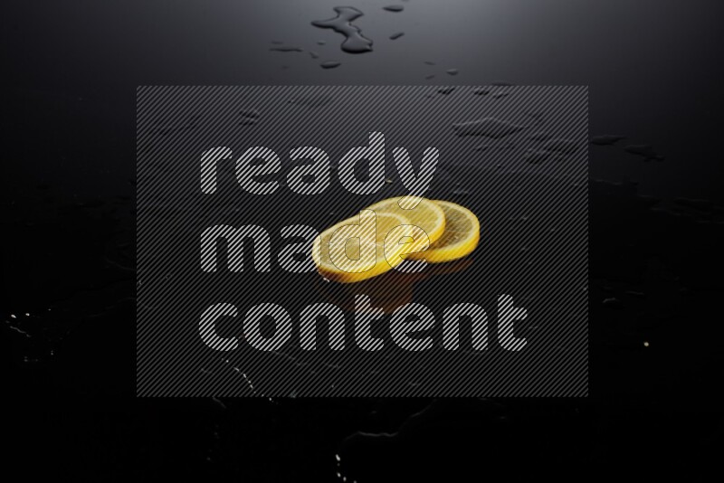 Lemon slices with water drops, and droplets on black background