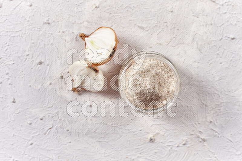 A glass jar full of onion powder on white background