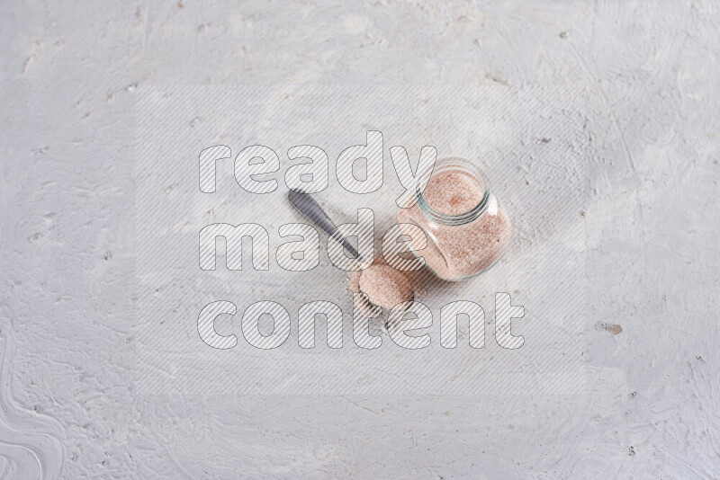 A glass jar full of fine himalayan salt on white background