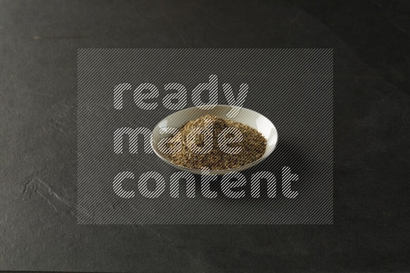 white ceramic round sauce dish filled with herbs on grey textured countertop