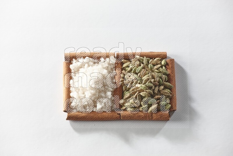 2 squares of cinnamon sticks full of cardamom and white salt on white flooring
