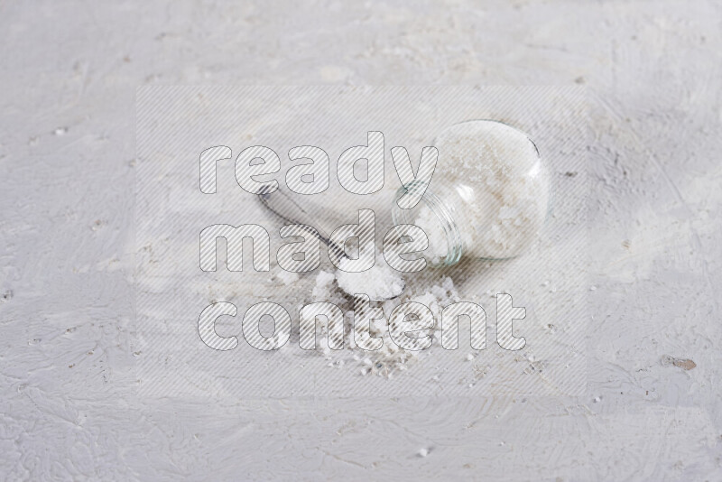 A glass jar full of coarse sea salt crystals on white background
