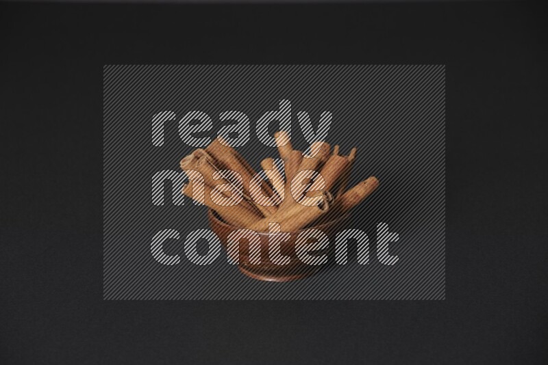 Cinnamon Sticks in a wooden bowl on black background