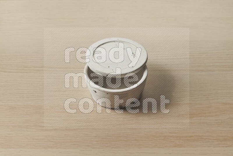 A white pottery bowl on light wooden background