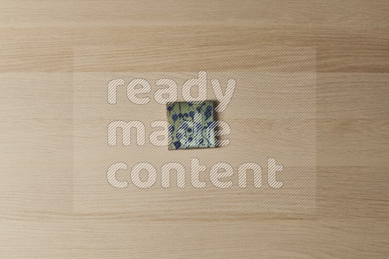 A decorative pottery coaster on light wooden background