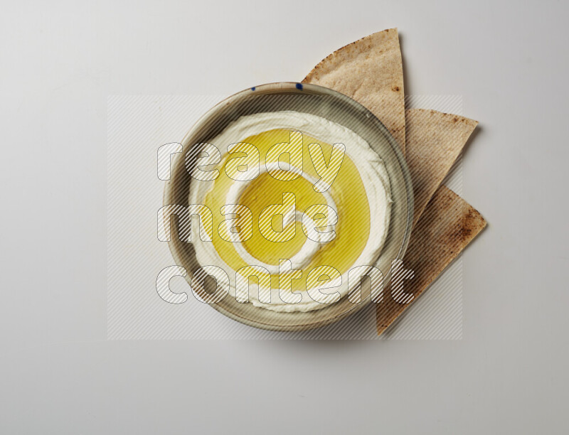 Lebnah garnished with olive oil in a grey pottery plate on a white background