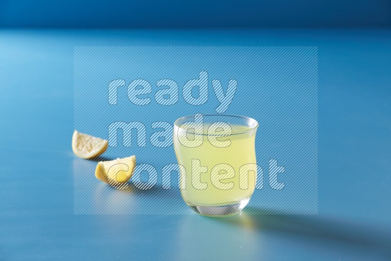 glass of lemon juice on blue background