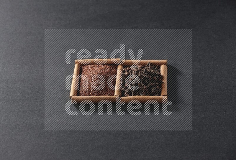 2 squares of cinnamon sticks full of garden cress and cloves on black flooring