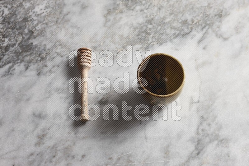 Multicolored pottery cup with wooden honey dipper on the side on grey marble background