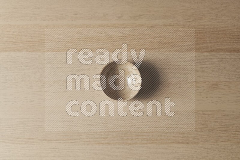 A beige pottery bowl on light wooden background