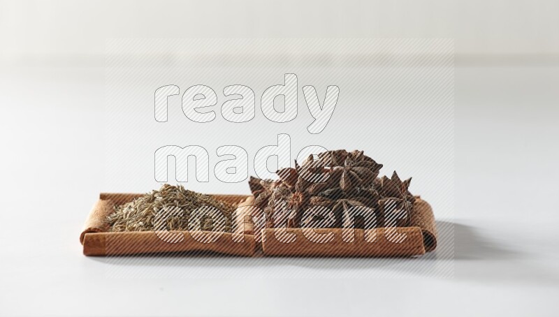 2 squares of cinnamon sticks full of star anise and cumin on white flooring