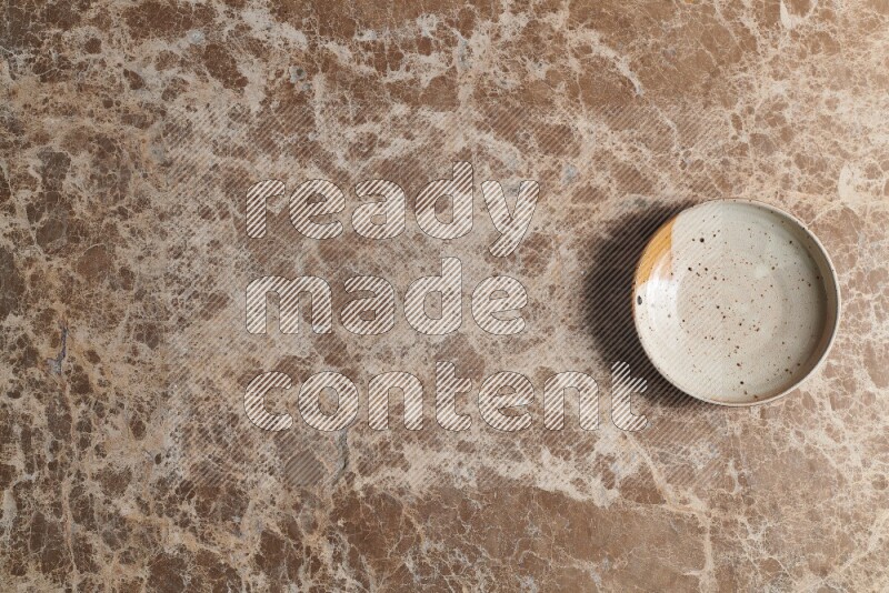 A multicolored pottery bowl on beige marble background