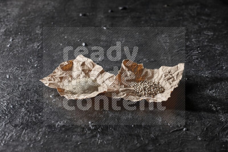 حبات ومسحوق الفلفل الأبيض في ورقتين على أرضية سوداء