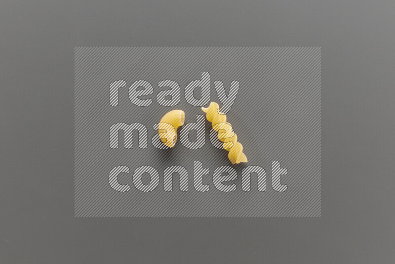 Elbow pasta with other types of pasta on grey background