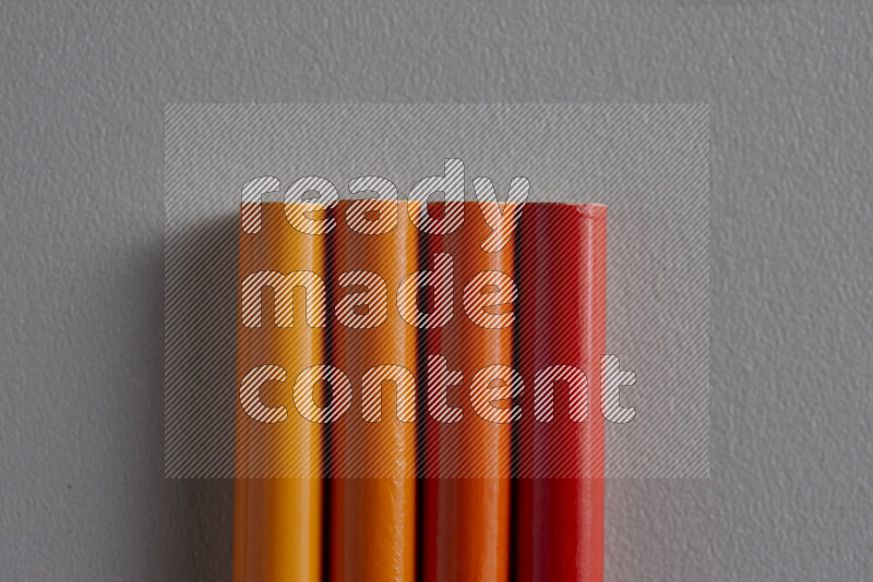 A collection of colored pencils arranged showcasing a gradient of orange hues on grey background