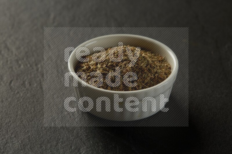 white ceramic round sauce bowl filled with herbs on grey textured countertop