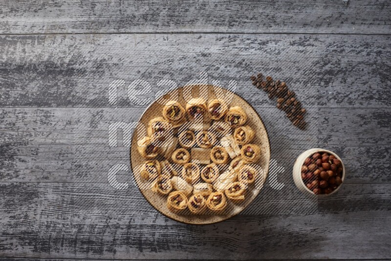 Oriental sweets in a pottery plate with nuts, coffee and honey in a dark setup