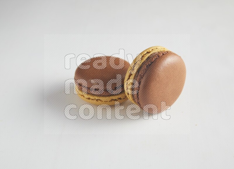 45º Shot of two Yellow and Brown Chai Latte macarons on white background