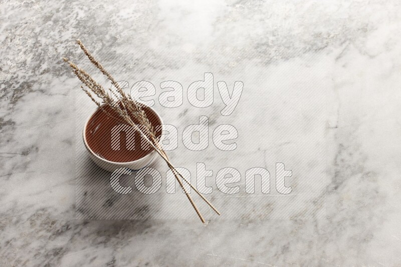 Wheat stalks on brown pottery bowl on grey marble background