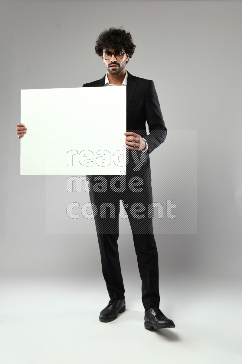 A man wearing formal standing and holding a white board on white background