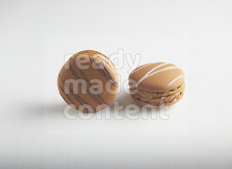 45º Shot of of two assorted Brown Irish Cream, and light brown  Almond Cream macarons on white background