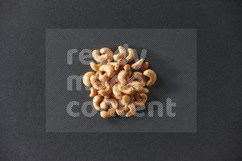 A bunch of cashews on a black background in different angles