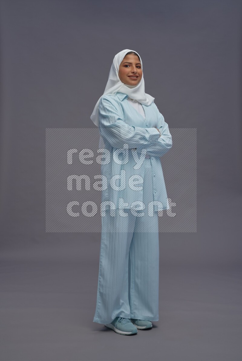 Saudi woman wearing hijab clothes standing with crossed arms on gray background