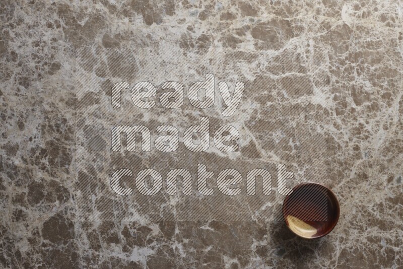 A wooden bowl on beige marble background