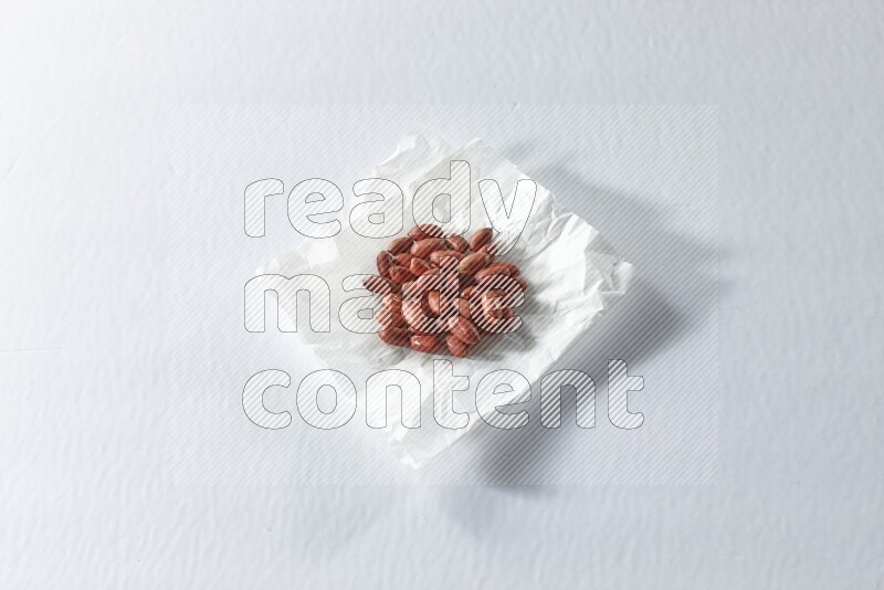 Red skin peanuts on a crumpled piece of paper on a white background in different angles