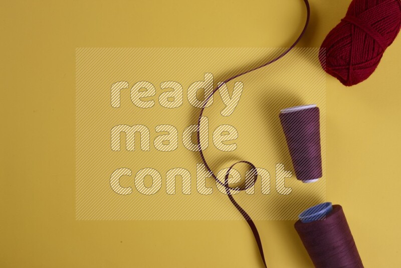 A red collection of sewing and tailoring tools arranged on a yellow background