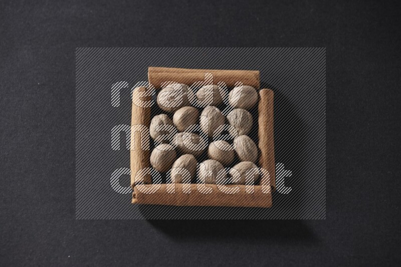 A single square of cinnamon sticks full of nutmeg on black flooring