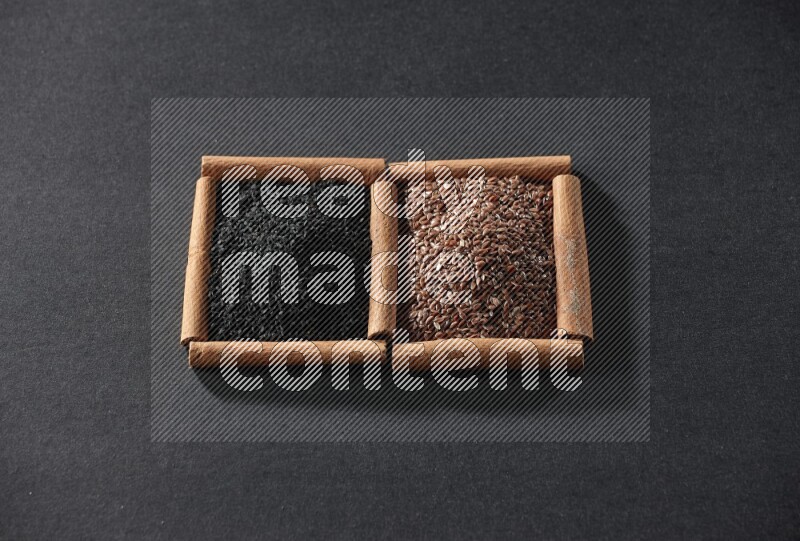 2 squares of cinnamon sticks full of flaxseeds and black seeds on black flooring