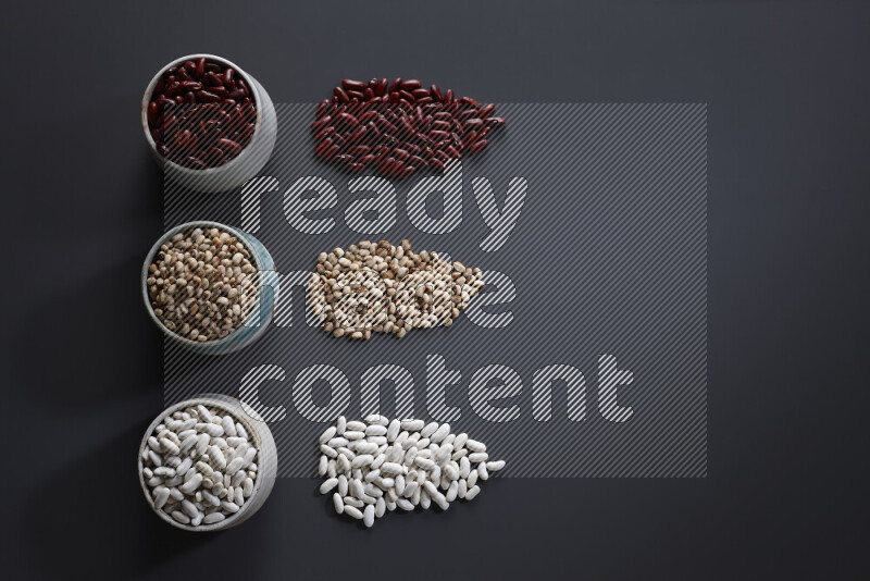 Legumes in pottery bowls on grey background