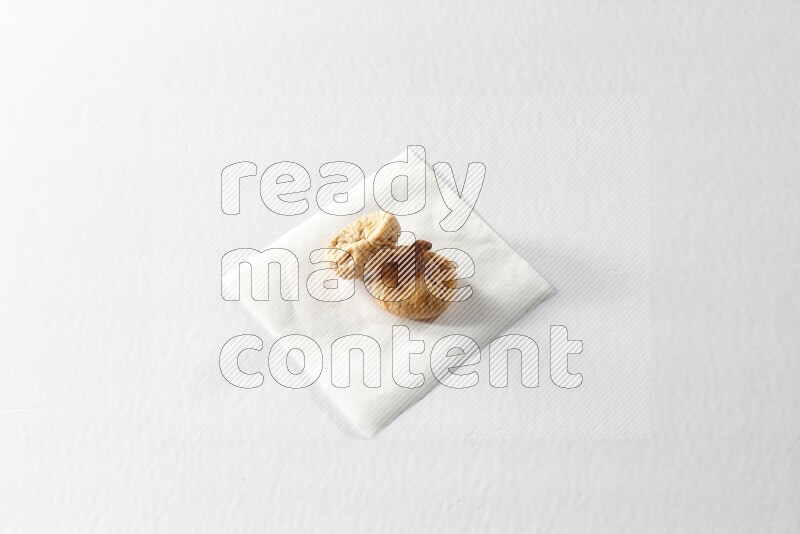 Two dried figs on a piece of paper on a white background in different angles