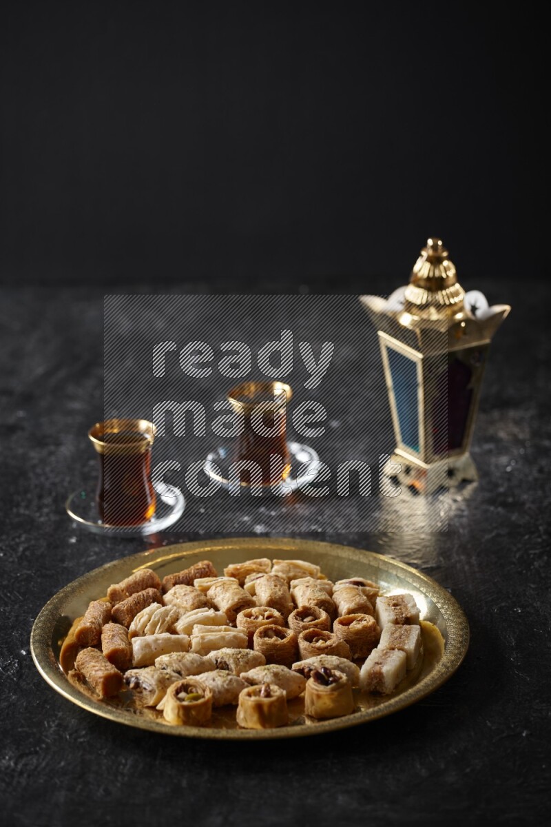 Oriental desserts with tea and a metal lantern in a dark setup