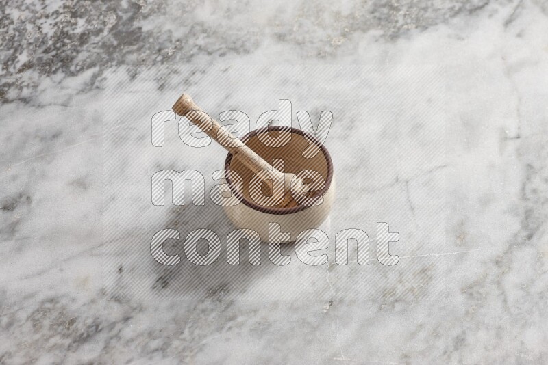 Beige Pottery oven bowl with wooden honey handle on the side with grey marble flooring, 65 degree angle