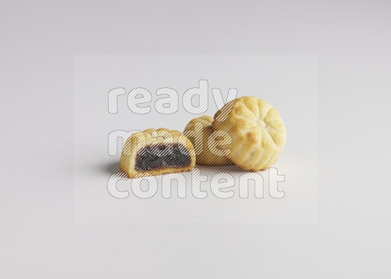 Three Pieces of Maamoul filled with date one of them is cut direct on white background