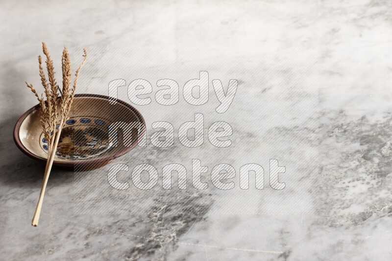 Wheat stalks on decorative pottery plate on grey marble background