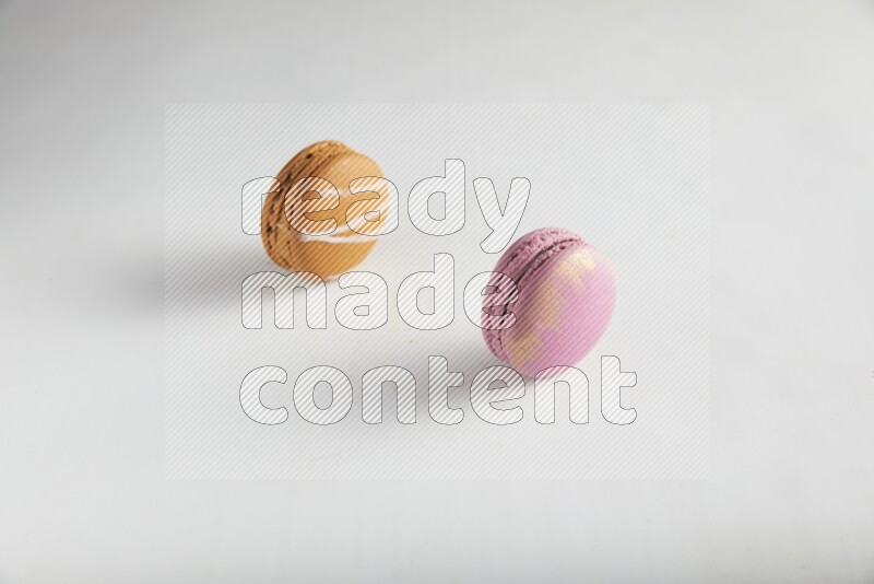 45º Shot of of two assorted Brown Irish Cream, and Purple Strawberry macarons on white background